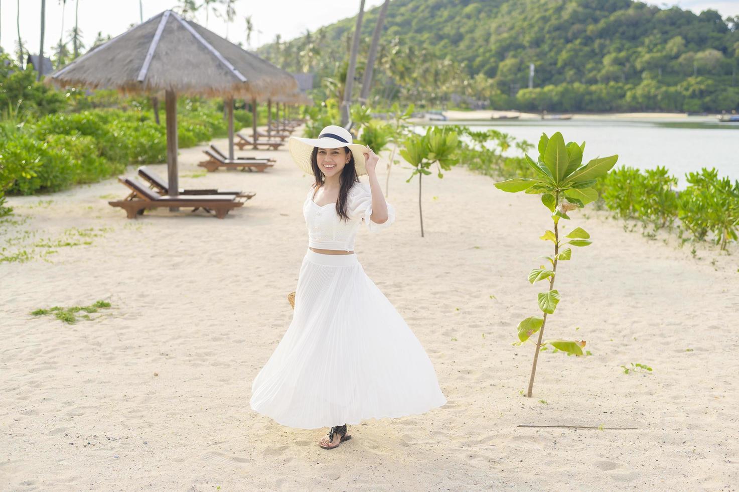 une belle femme heureuse en robe blanche appréciant et se relaxant sur le concept de plage, d'été et de vacances photo