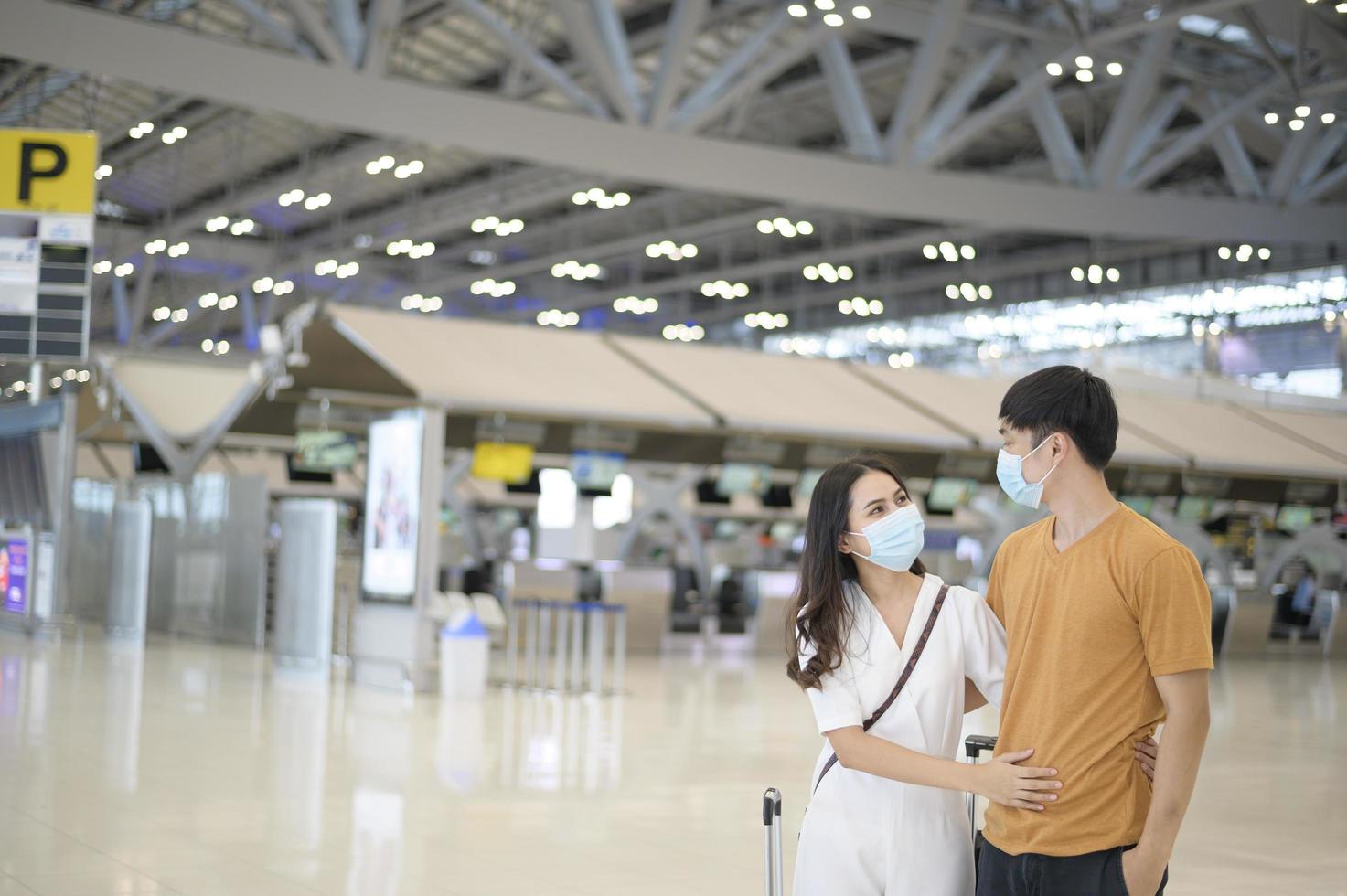 un couple asiatique porte un masque de protection à l'aéroport international, voyage sous la pandémie de covid-19, voyages de sécurité, protocole de distanciation sociale, nouveau concept de voyage normal . photo