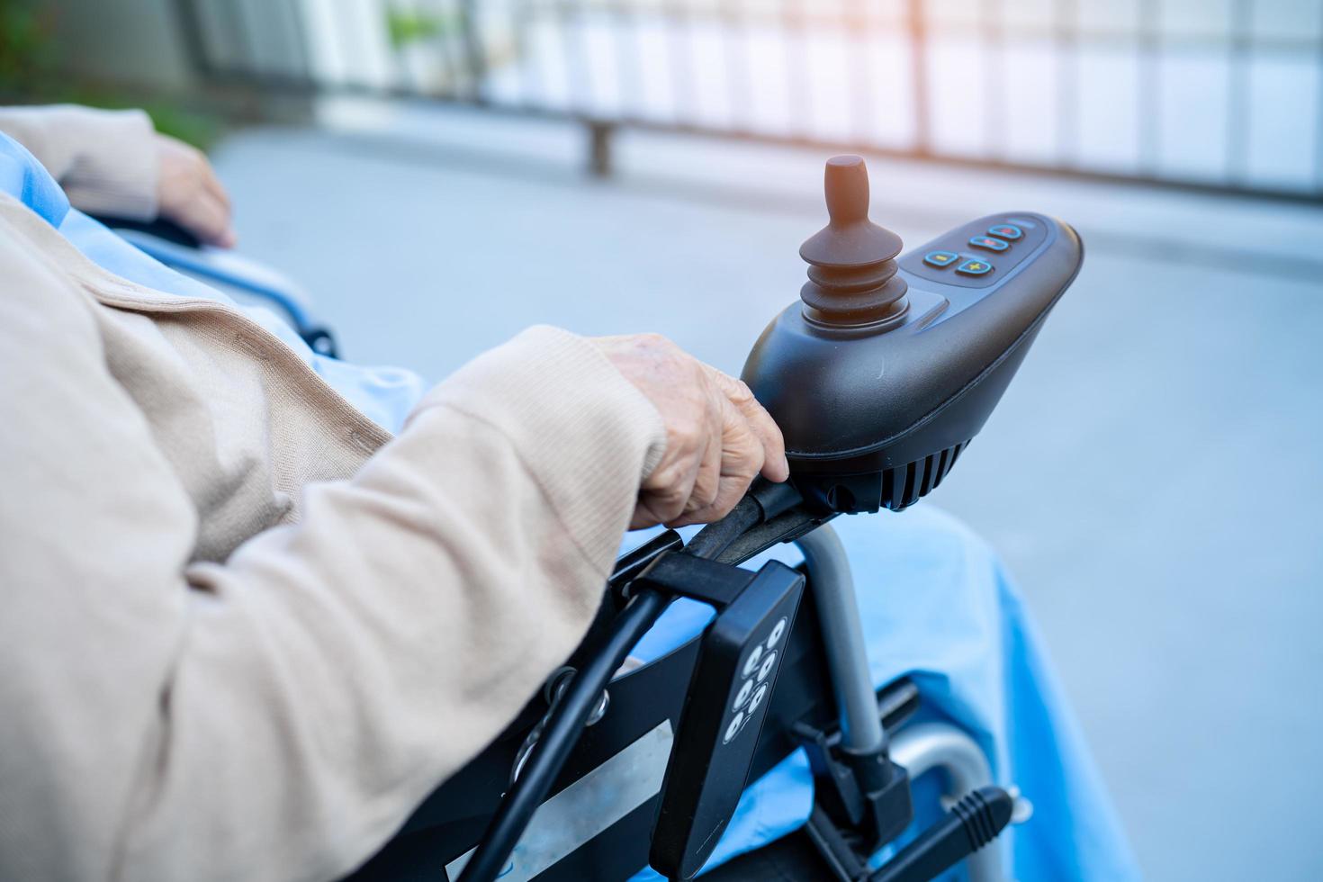 patiente asiatique âgée ou âgée vieille dame sur fauteuil roulant électrique avec télécommande à l'hôpital de soins infirmiers, concept médical solide et sain photo