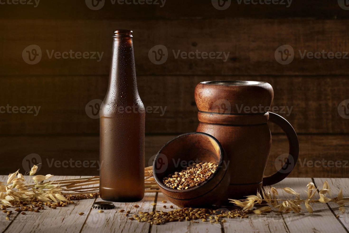 verre et bouteille de bière, épis d'orge sur fond de bois. ale. photo