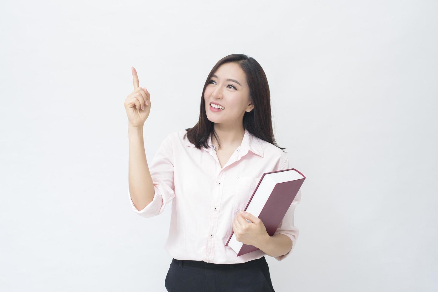 Portrait d'une belle étudiante en chemise rose tient un livre isolé sur fond blanc studio photo