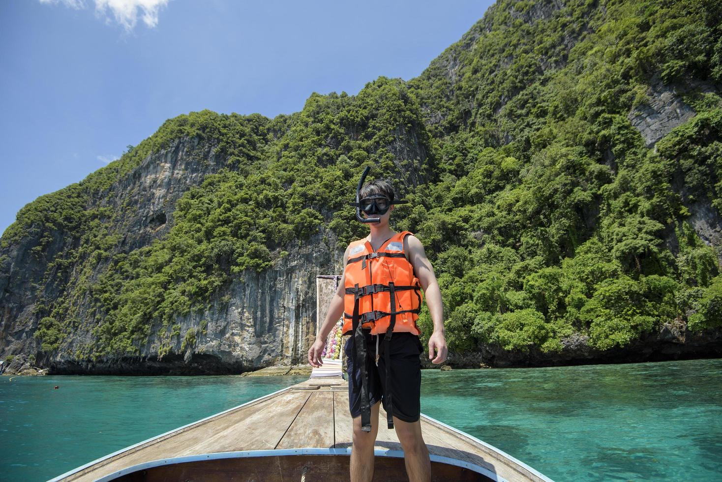 un homme actif sur un bateau traditionnel thaïlandais à longue queue est prêt à plonger et à plonger, îles phi phi, thaïlande photo