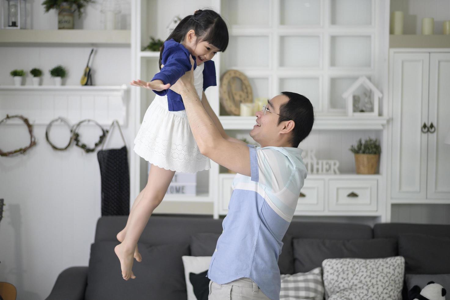 un père en bonne santé tient une fille mignonne heureuse volant et jouant à l'avion ensemble à la maison le week-end, concept de famille. photo