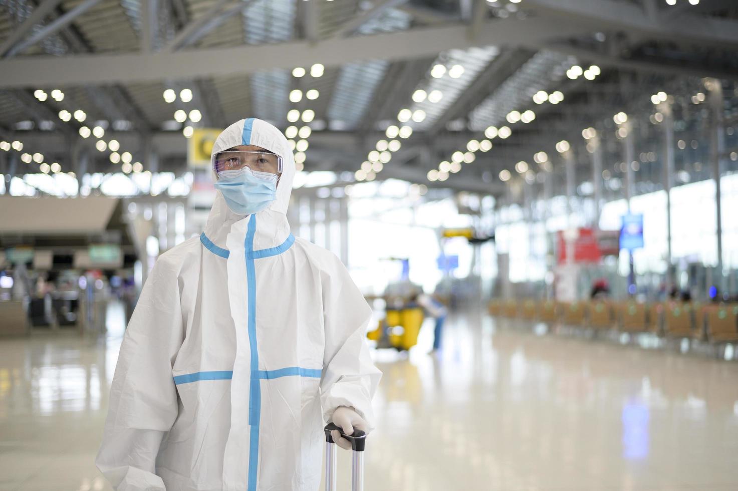 un homme asiatique porte un costume ppe à l'aéroport international, voyage en toute sécurité, protection contre le covid-19, concept de distanciation sociale photo