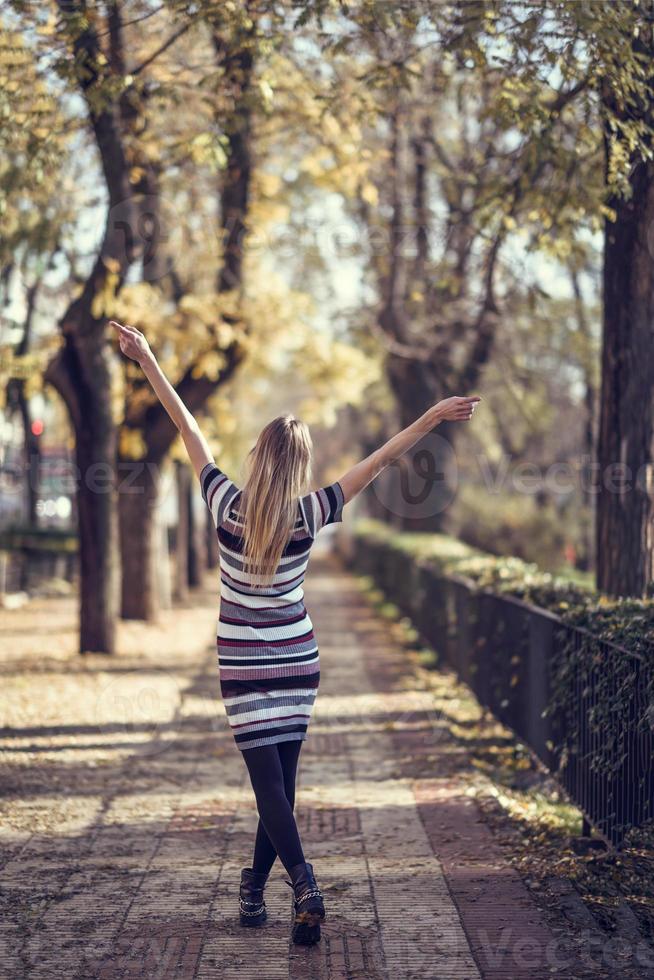 jeune femme blonde marchant dans la rue en levant les bras photo