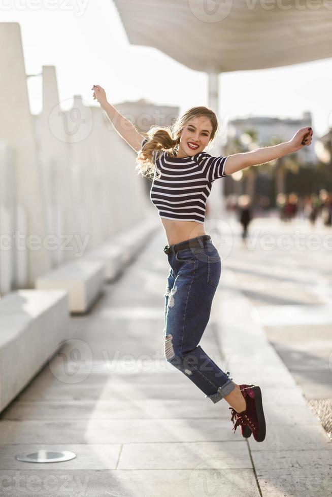 drôle de femme blonde sautant en arrière-plan urbain. photo