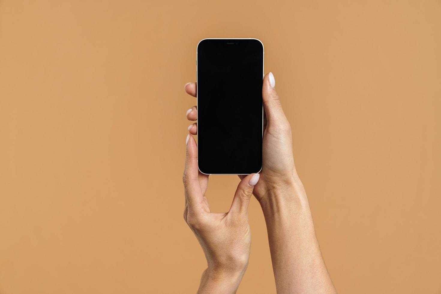 femme tient un écran de téléphone à l'appareil photo à deux mains