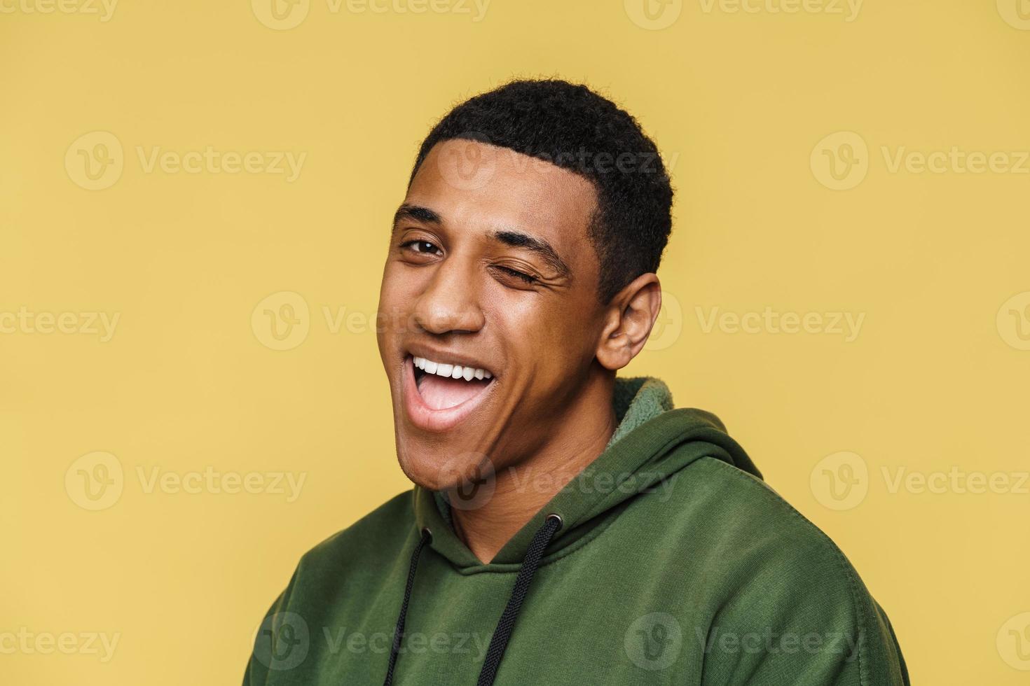 portrait d'un homme africain souriant en sweat à capuche faisant un clin d'œil à la caméra photo