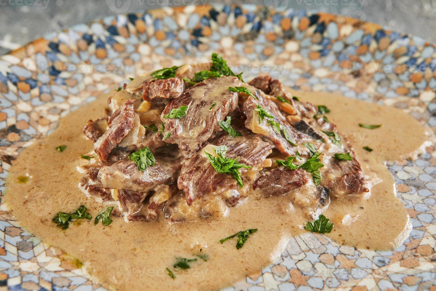 stroganoff de boeuf sur une assiette et des ustensiles de cuisine. cuisine gastronomique française photo