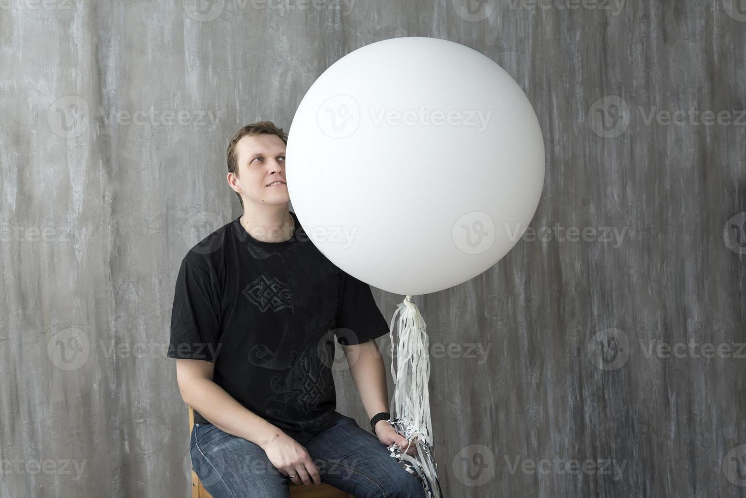 un homme tenant un ballon gonflable sur fond gris. photo