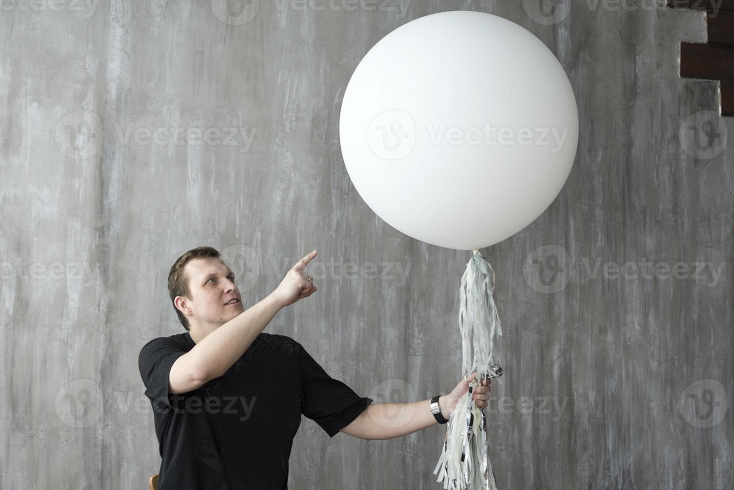 un homme tenant un ballon gonflable sur fond gris. photo