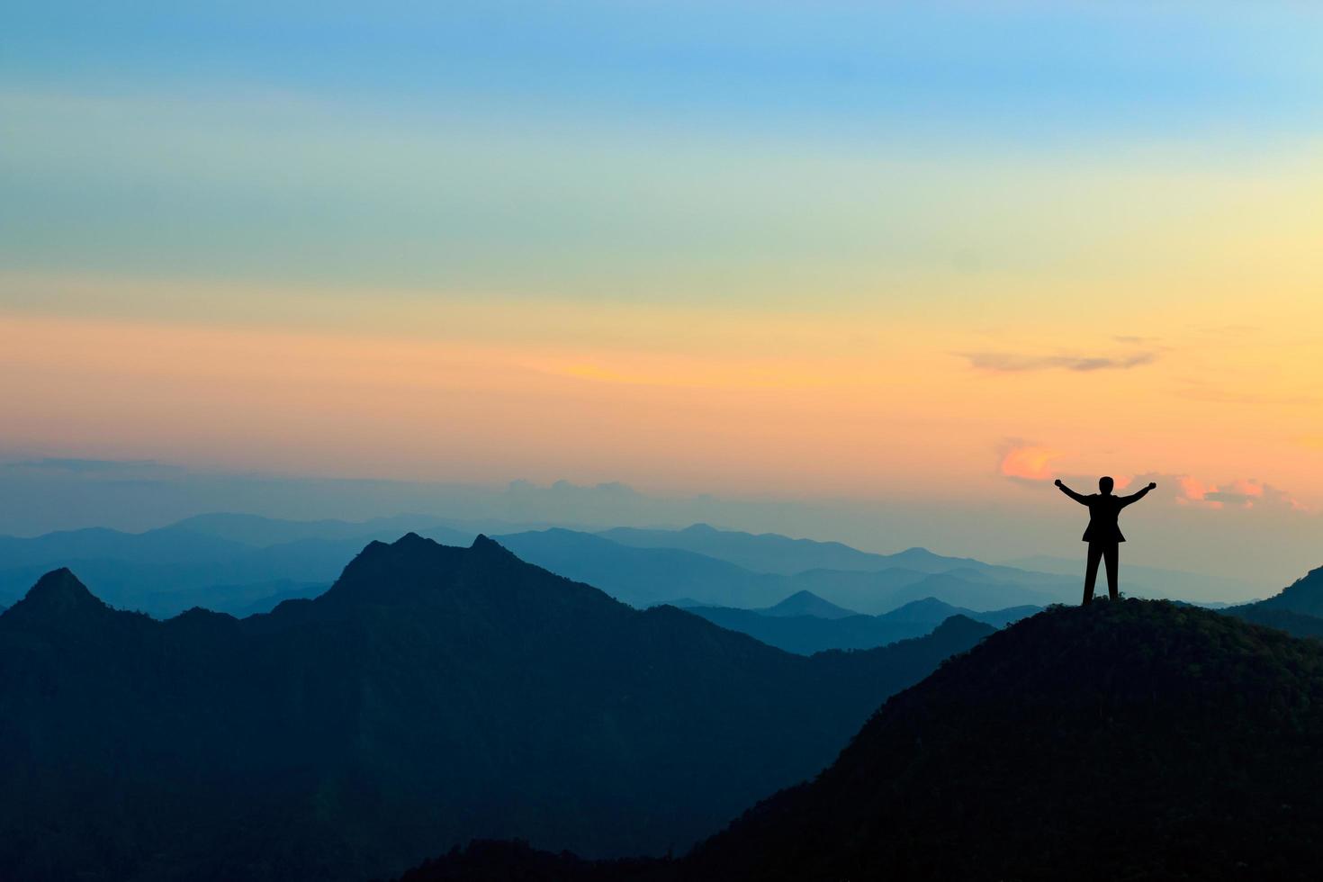 silhouette d'homme d'affaires au sommet d'une montagne sur fond de ciel coucher de soleil, concept d'entreprise, de succès, de leadership et de réussite photo