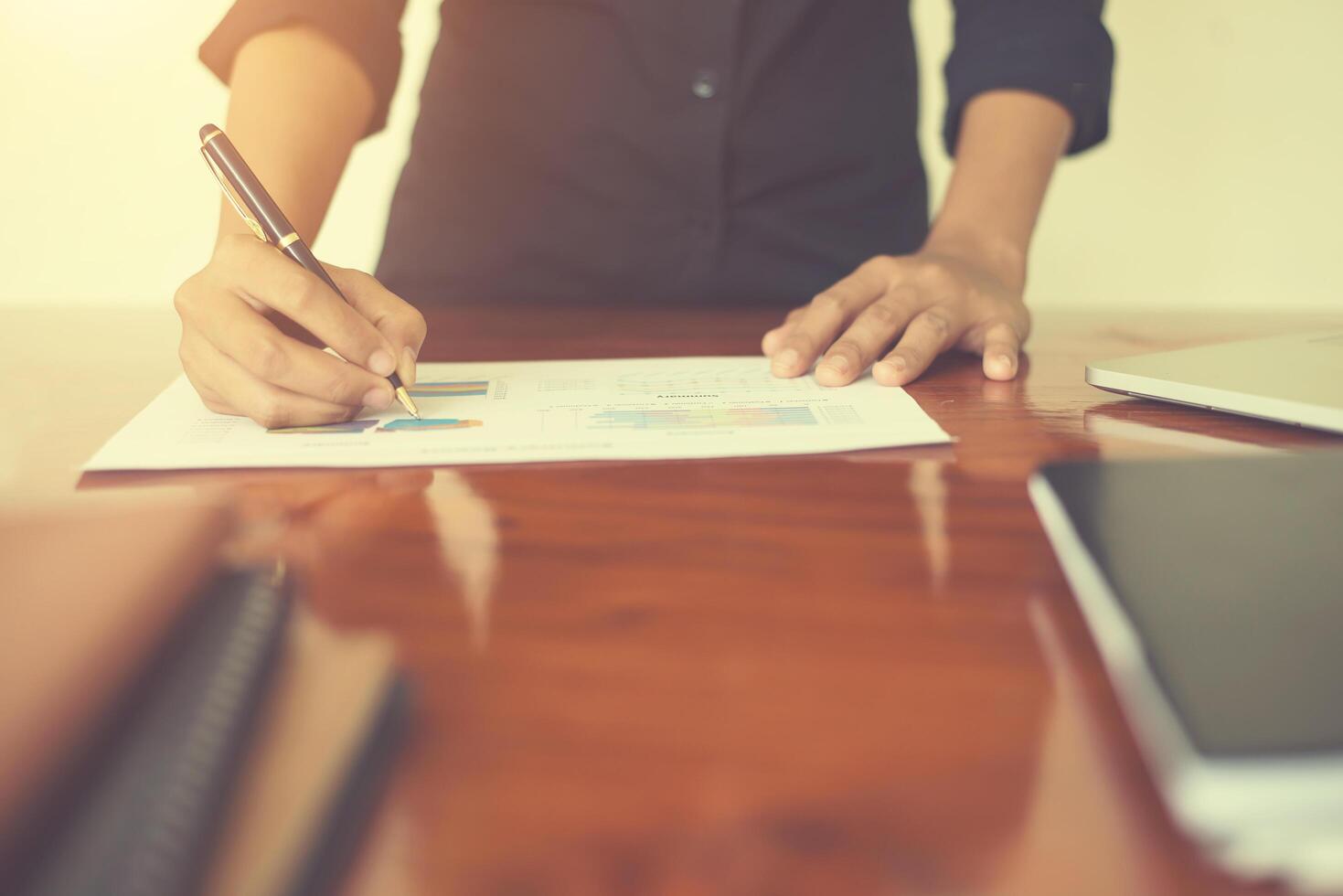 main de femme avec un stylo écrit sur le papier d'affaires. tableau de rapport, occupé au travail. photo