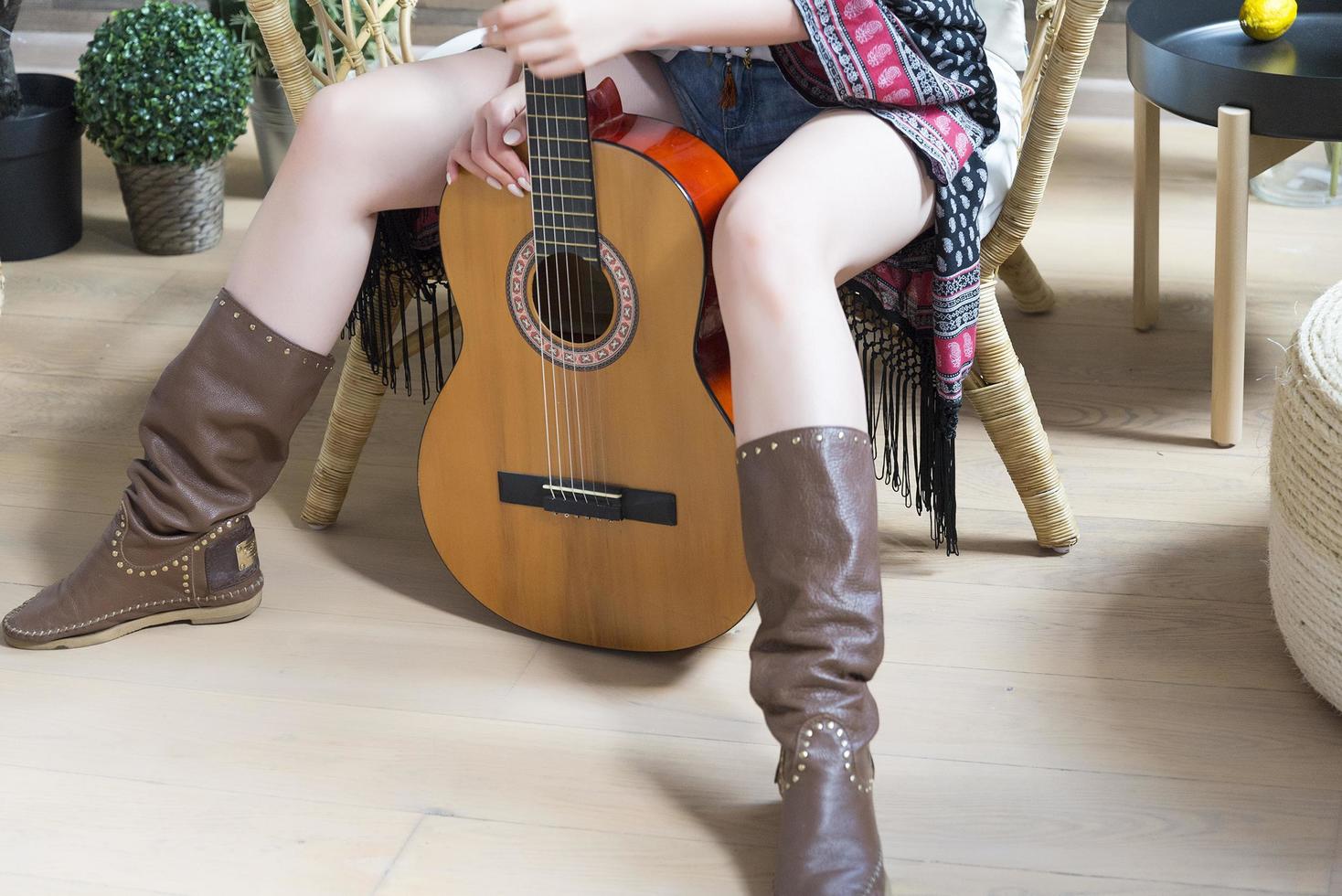 jambes dans des bottes de cow-boy en cuir et une guitare à sept cordes. photo