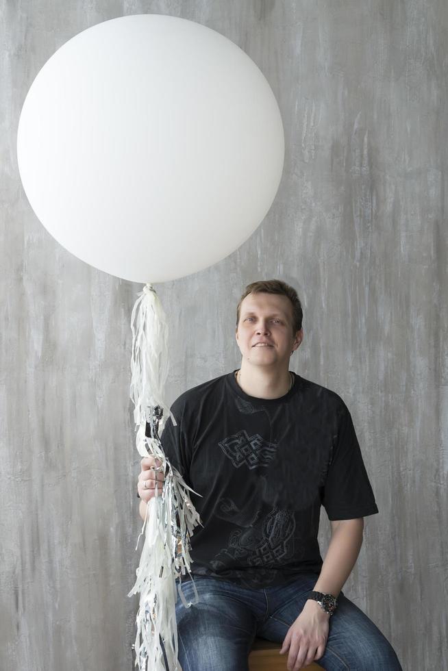 un homme tenant un ballon gonflable sur fond gris. photo