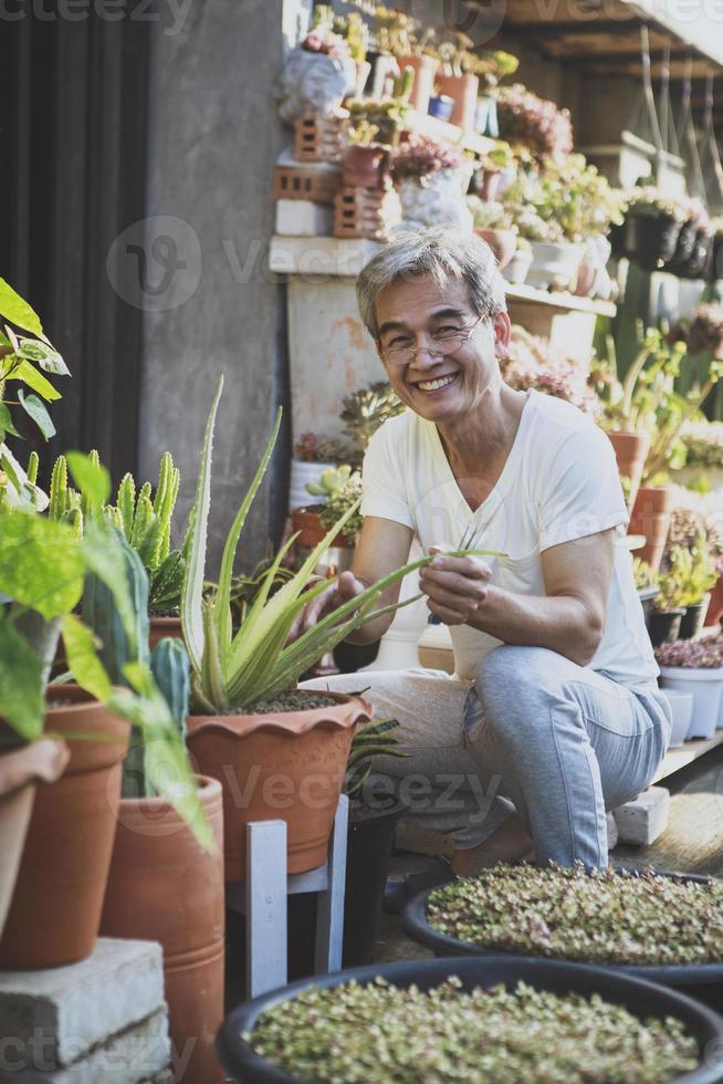 homme senior asiatique souriant avec bonheur face assis dans le jardin de la maison photo