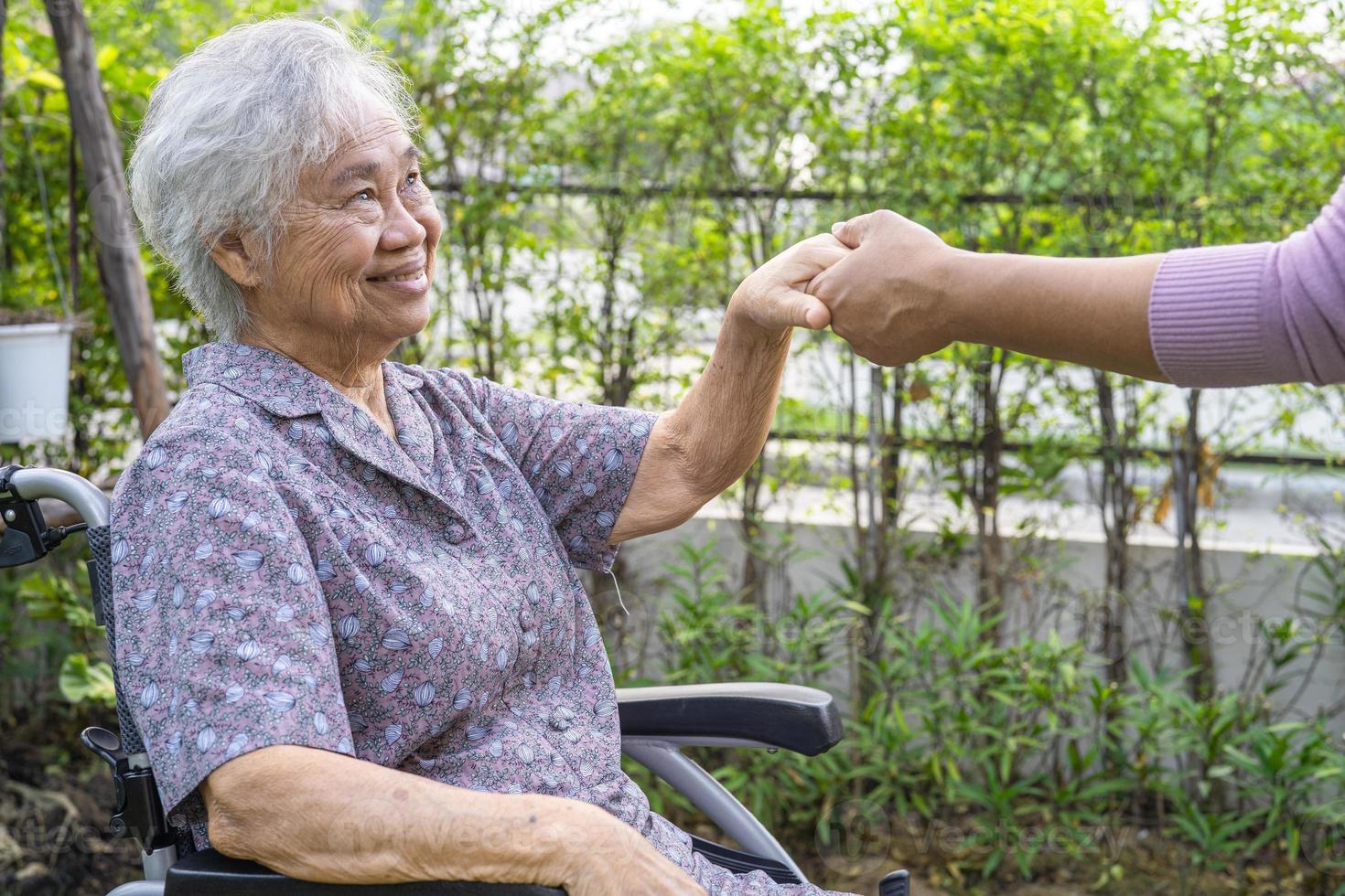 tenant par la main une vieille dame asiatique âgée ou âgée patiente avec amour, soins, encouragement et empathie au parc. photo