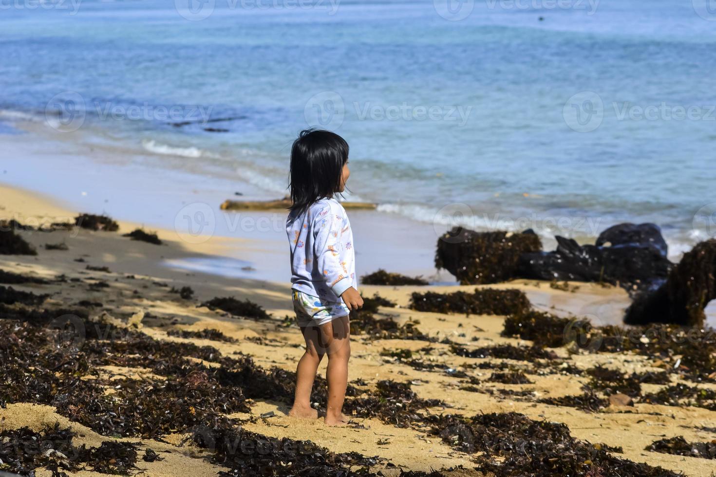 une petite fille jouant seule à la plage photo