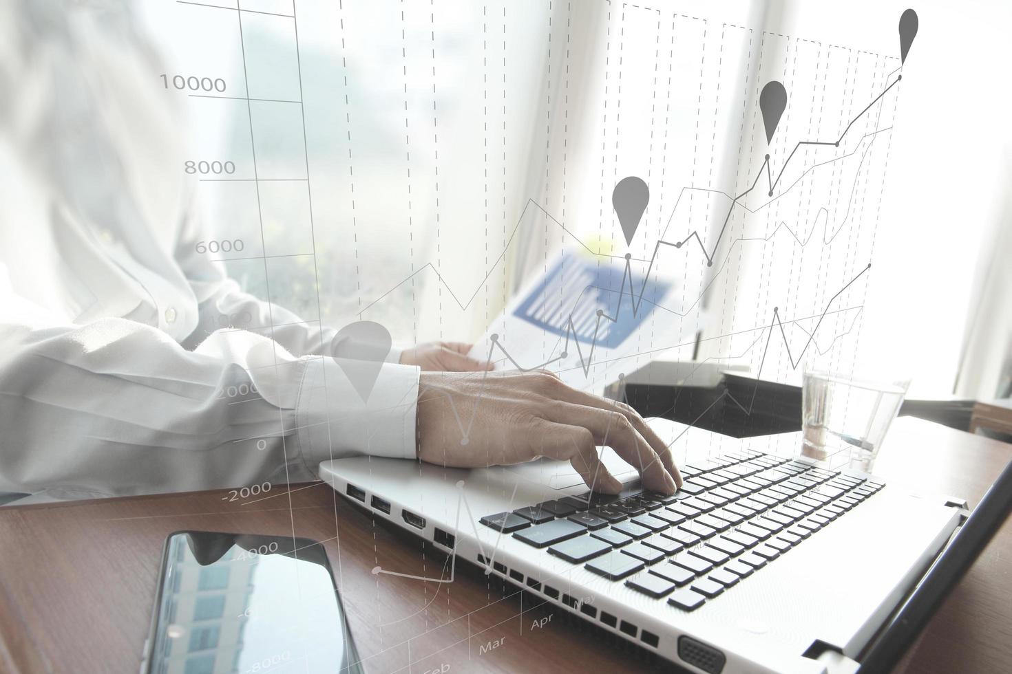 main d'homme d'affaires travaillant sur un ordinateur portable sur un bureau en bois comme concept et diagramme d'entreprise graphique photo