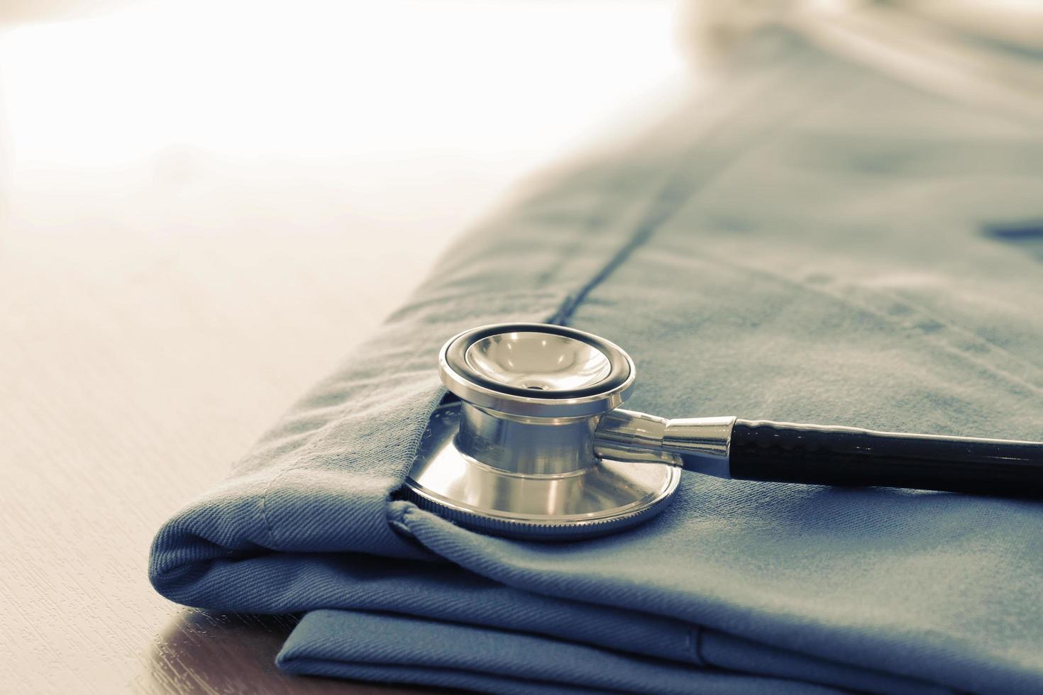 stéthoscope avec manteau de médecin bleu sur table en bois avec dof peu profond uniformément assorti et arrière-plan photo