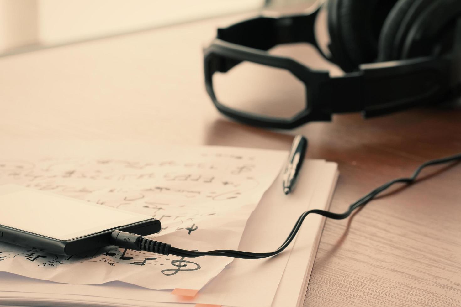 gros plan du smartphone avec casque sur papier de notes de musique sur un bureau en bois photo