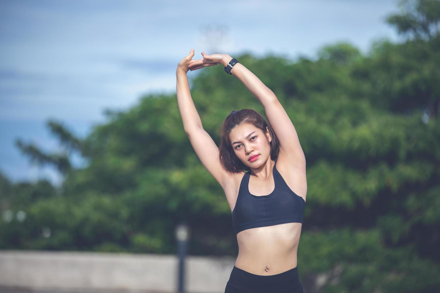 femme athlétique asiatique échauffement et jeune athlète féminine assise sur un exercice et s'étirant dans un parc avant le coureur à l'extérieur, concept de mode de vie sain photo