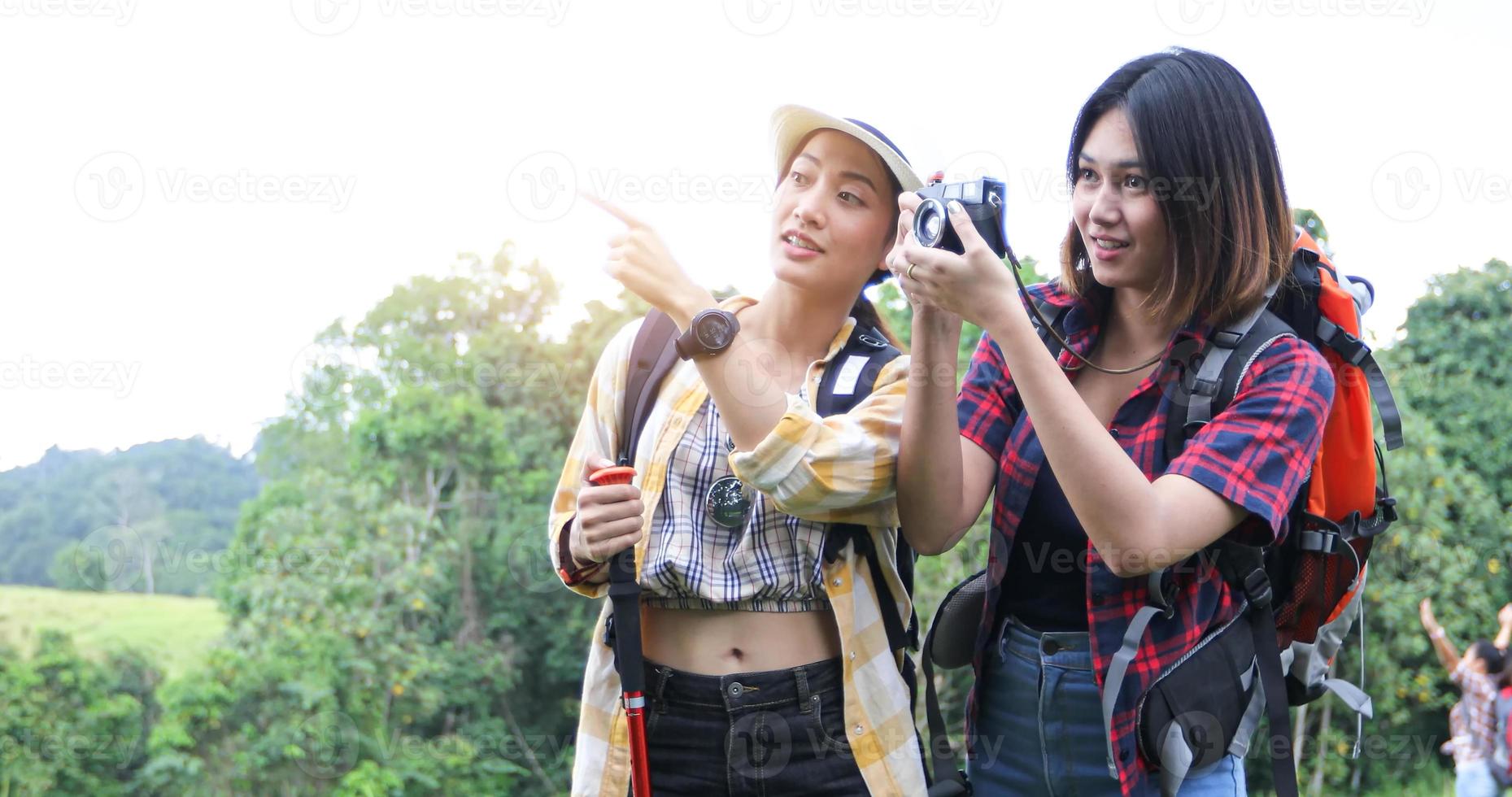 groupe asiatique de jeunes faisant de la randonnée avec des sacs à dos d'amis marchant ensemble et regardant la carte et prenant un appareil photo au bord de la route et ayant l'air heureux, détendez-vous en voyage de concept de vacances