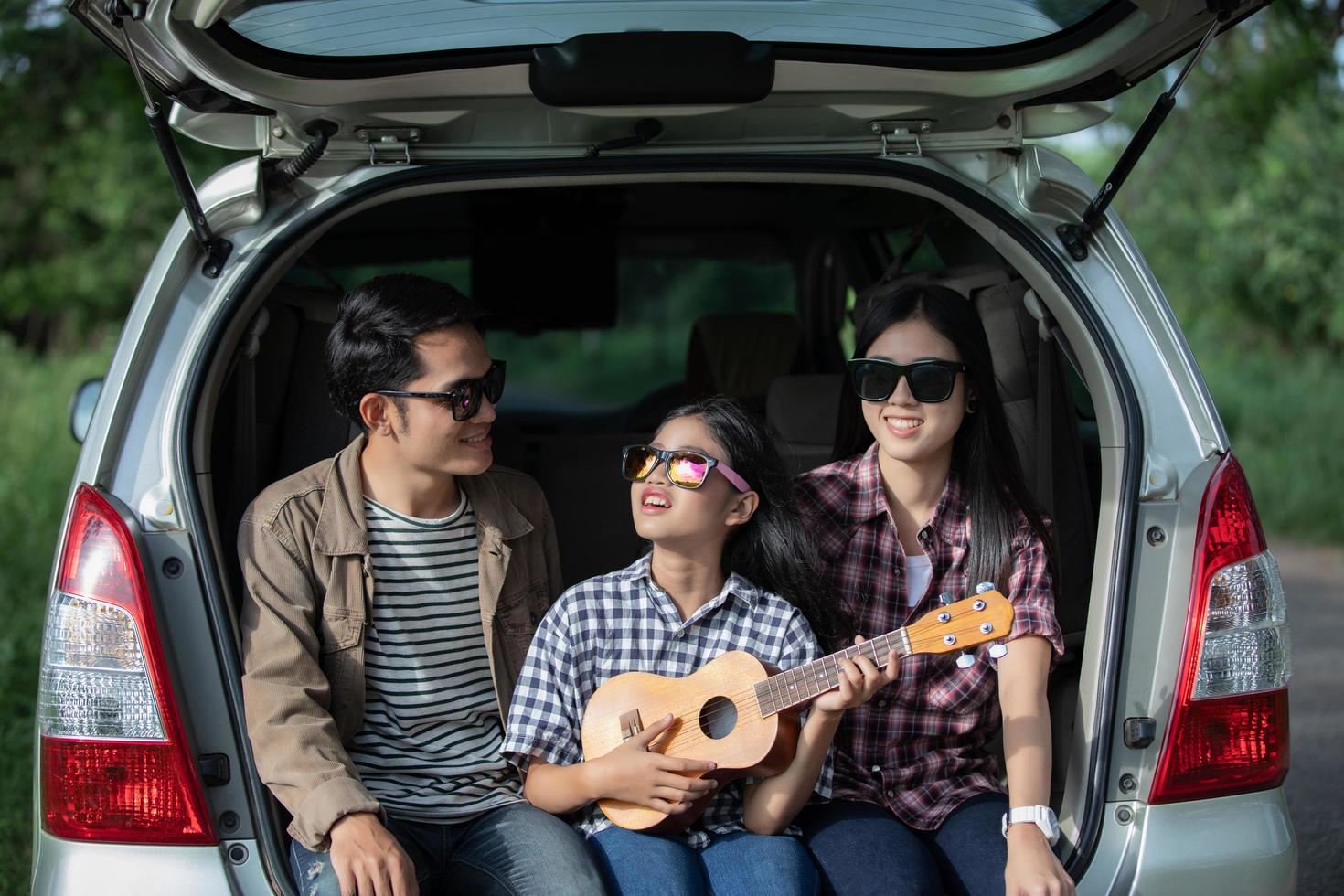 heureuse petite fille avec une famille asiatique assise dans la voiture pour profiter d'un voyage sur la route et de vacances d'été en camping-car photo