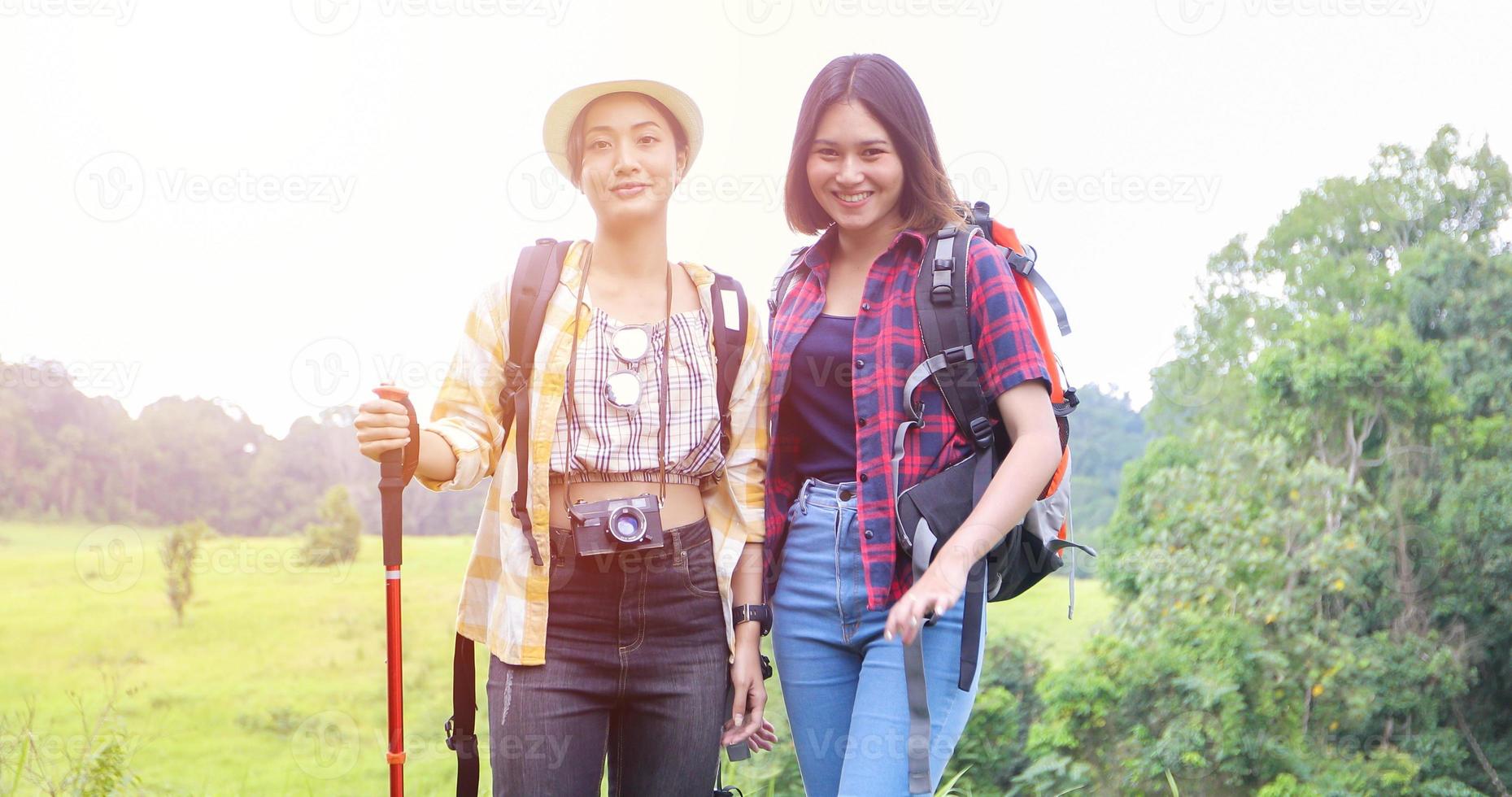 groupe asiatique de jeunes faisant de la randonnée avec des sacs à dos d'amis marchant ensemble et regardant la carte et prenant un appareil photo au bord de la route et ayant l'air heureux, détendez-vous en voyage de concept de vacances