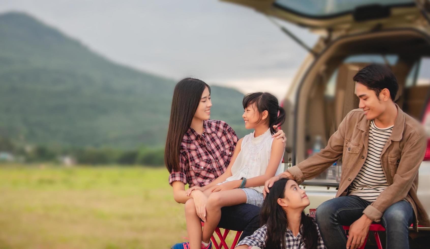 heureuse petite fille avec une famille asiatique assise dans la voiture pour profiter d'un voyage sur la route et de vacances d'été en camping-car photo