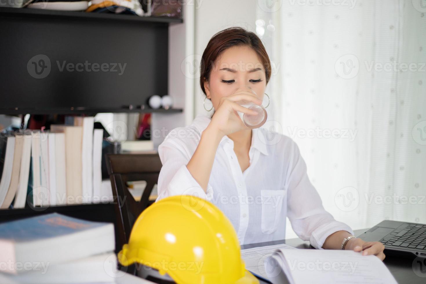 femmes d'affaires asiatiques et femmes d'ingénierie utilisant un ordinateur portable pour travailler et boire de l'eau photo