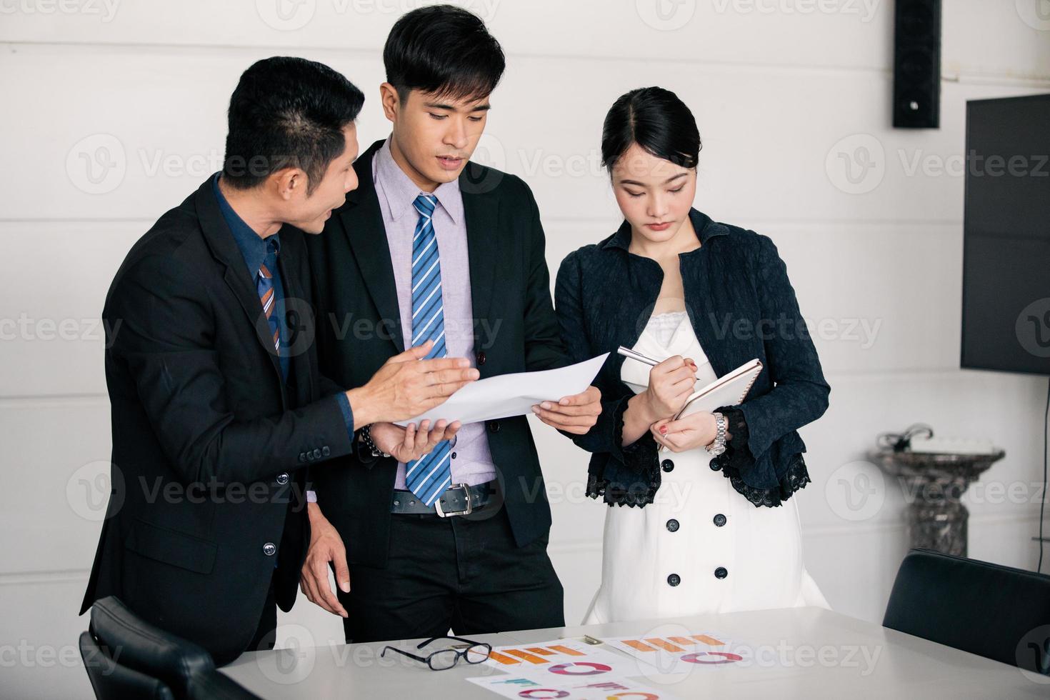 hommes d'affaires travaillant et pointant sur un diagramme financier graphique et des documents d'analyse sur une table de bureau photo