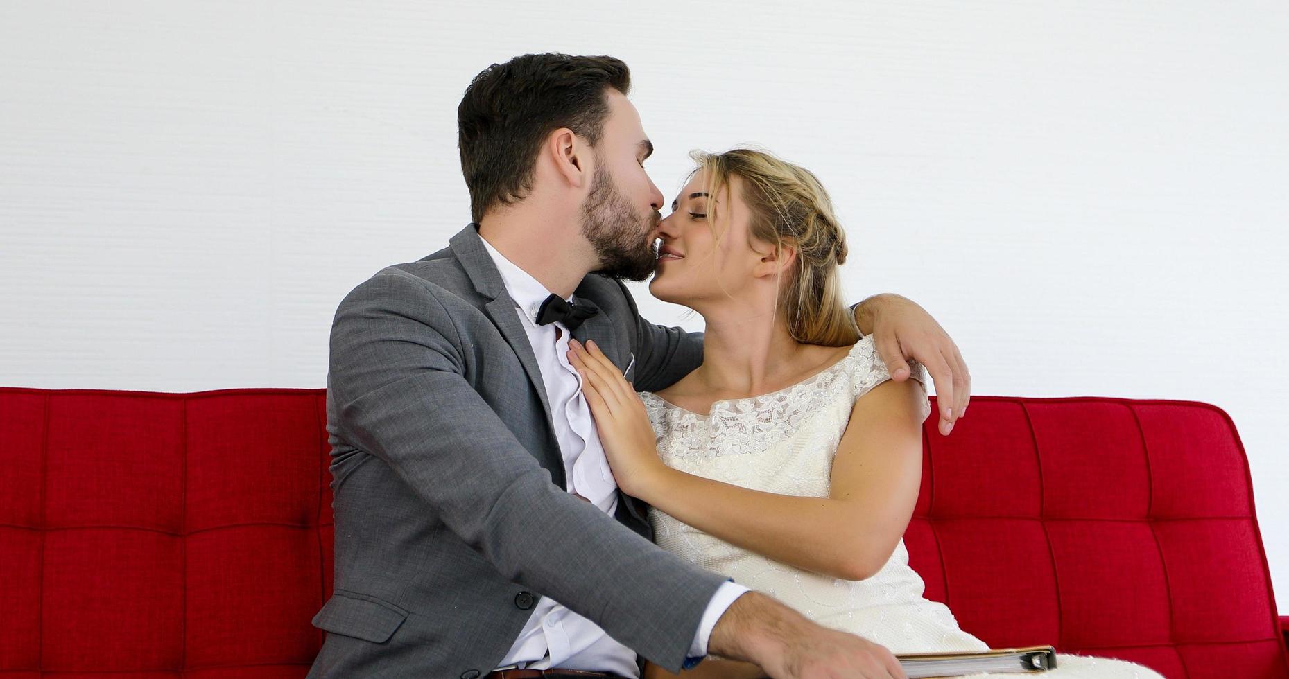 les amoureux donnent des fleurs à la mariée et s'embrassent heureux et le couple aime debout dans le studio de mariage photo