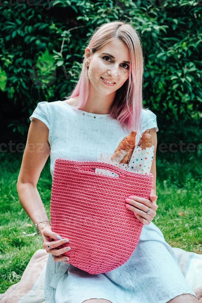 femme vêtue d'une robe tenant un sac avec des baguettes de pain assis sur un plaid dans le parc photo