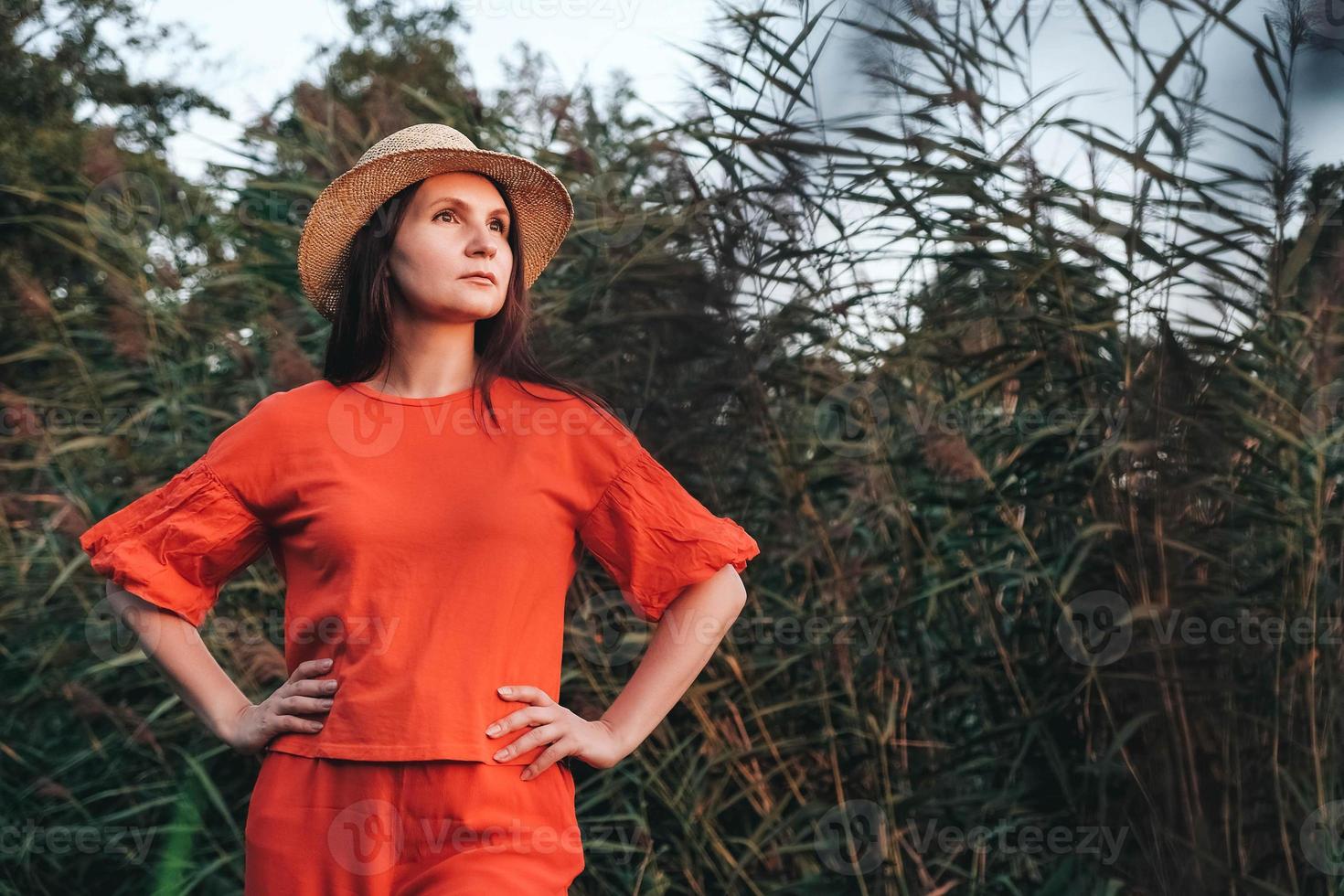 femme au chapeau de paille vêtue de vêtements rouges sur fond de roseaux photo