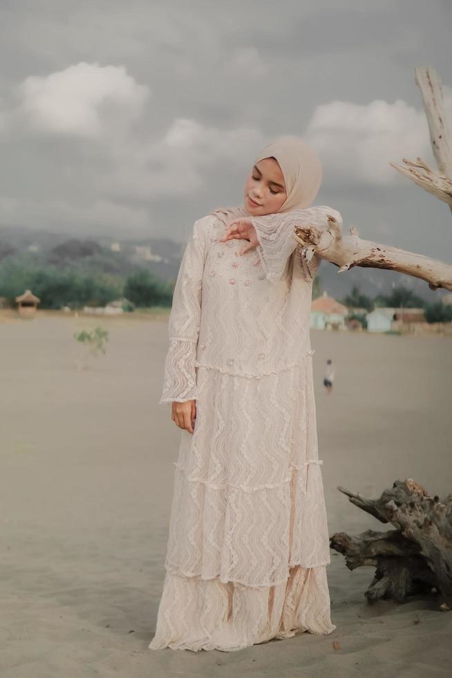 beau modèle féminin islamique portant la mode hijab, une robe de mariée moderne pour femme musulmane se promène le long du sable et de la mer. un modèle de fille asiatique utilisant le hijab s'amusant à la plage. photo avant mariage