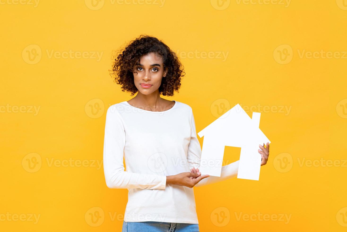 jolie femme afro-américaine tenant une découpe de maison isolée sur fond jaune photo