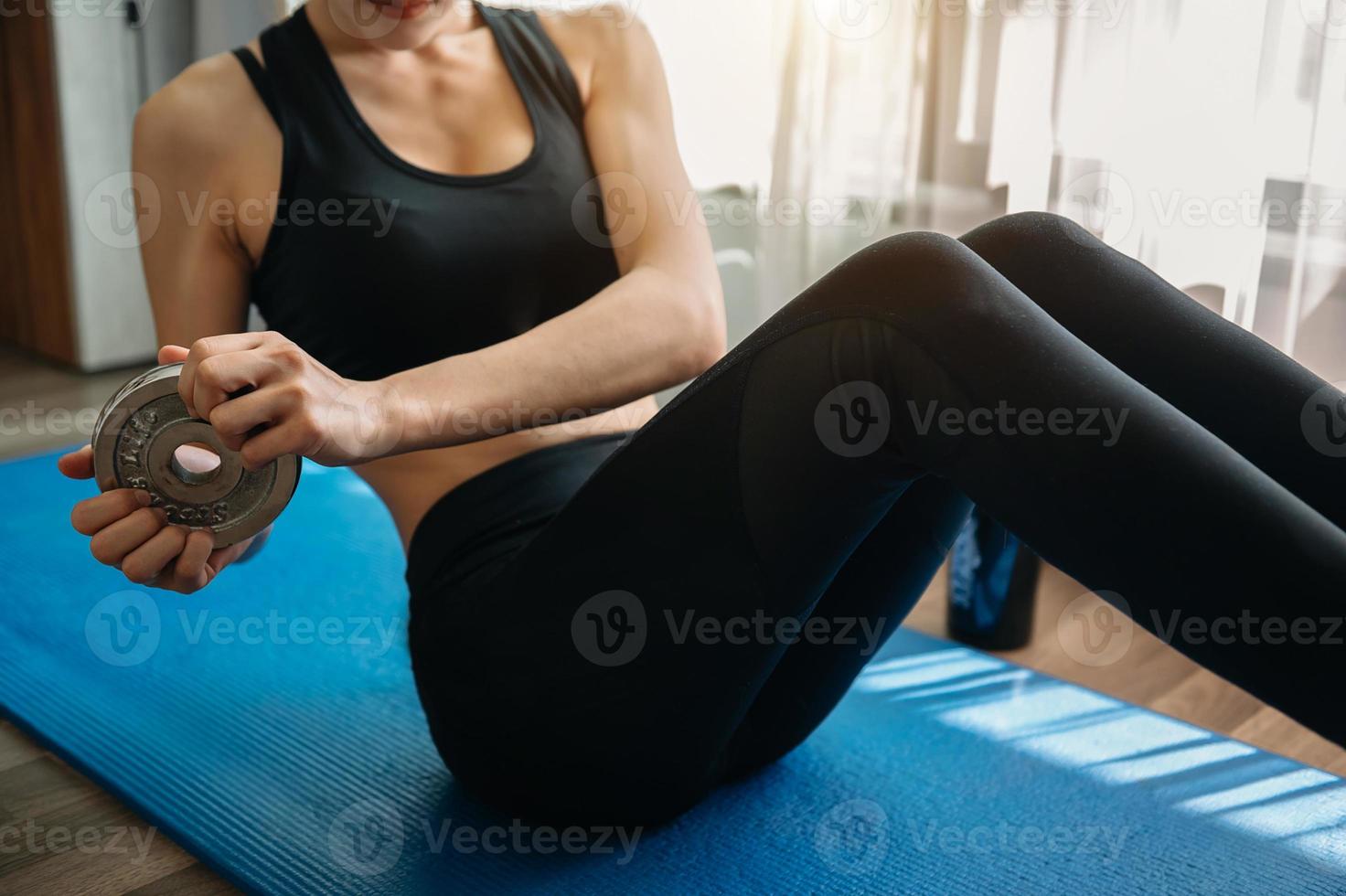 femme déterminée à perdre du poids à la maison et à faire de l'exercice avec des haltères. concept de sport et de loisirs. belle femme photo