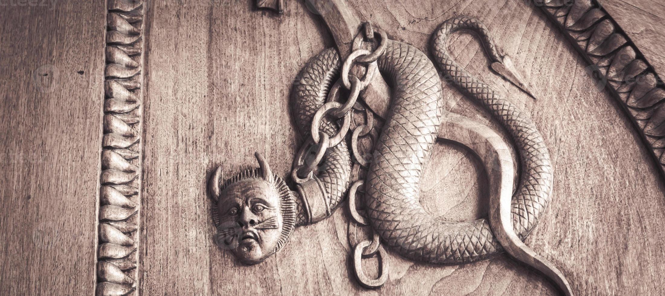 symbole du serpent diable. créature magique fantastique sur une vieille porte, abbaye du 12ème siècle en italie. photo