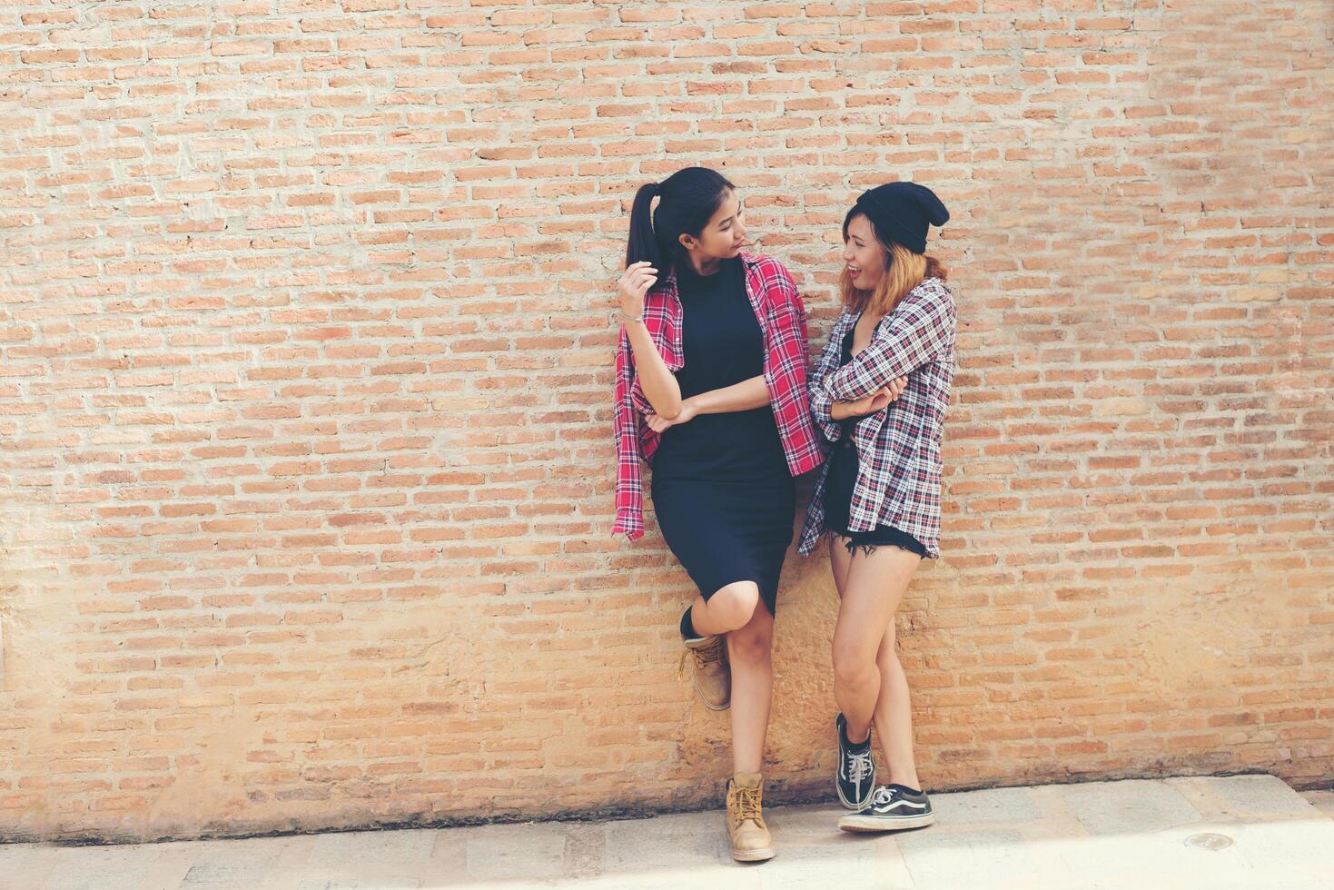 gros plan portrait de deux jolies hipster deux copines sourient, s'amusent contre le mur de briques urbain. photo