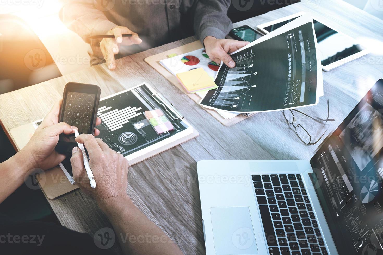 deux collègues homme d'affaires discutant de données et d'une tablette numérique et d'un ordinateur portable avec un téléphone intelligent avec une stratégie d'entreprise numérique sur un bureau en bois en tant que concept photo