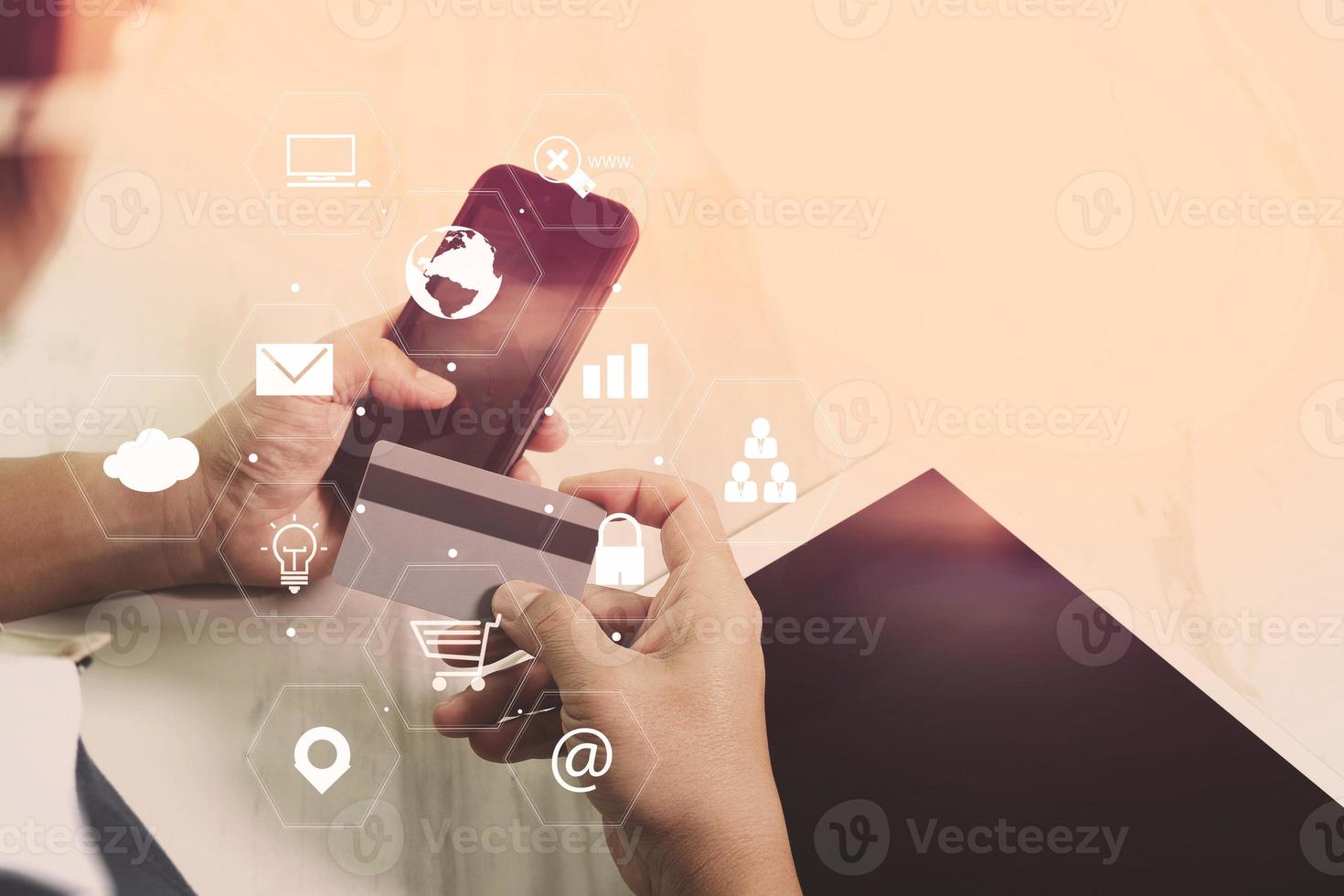 homme d'affaires travaillant avec un téléphone intelligent et une tablette numérique et une carte de crédit sur un bureau en bois dans un bureau moderne avec interface d'icônes virtuelles photo