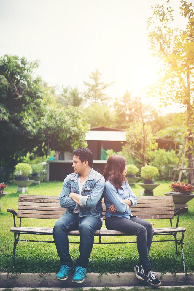 jeune couple mécontent assis sur un banc dans le parc, concept de style de vie de couple. photo