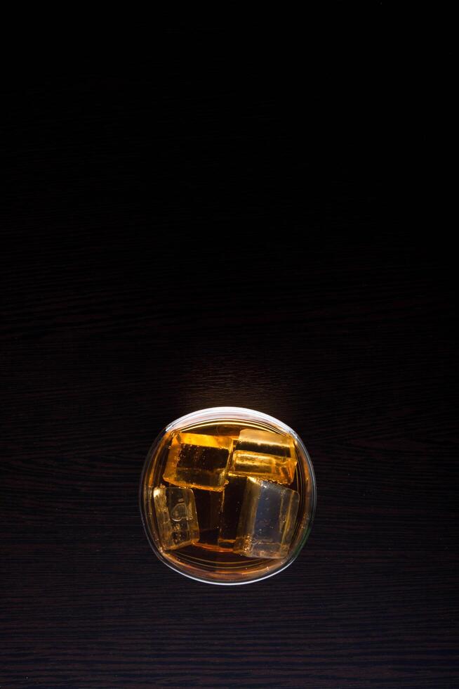 vue de dessus du whisky en verre avec de la glace sur fond noir photo