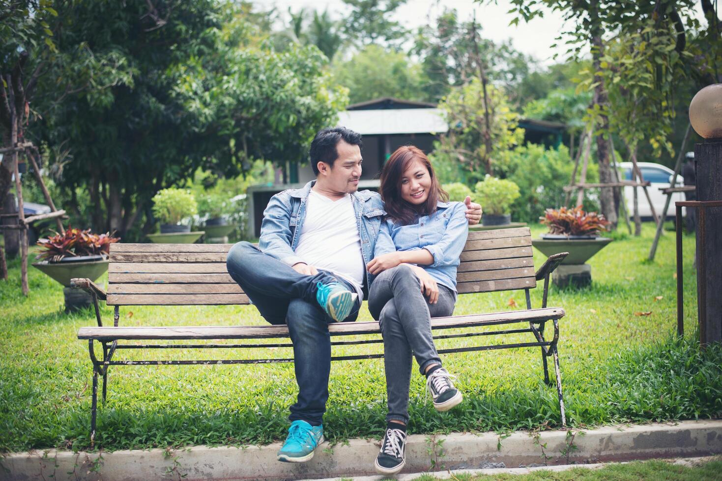 jeune couple souriant se regardant assis sur un banc, datant du temps ensemble. photo