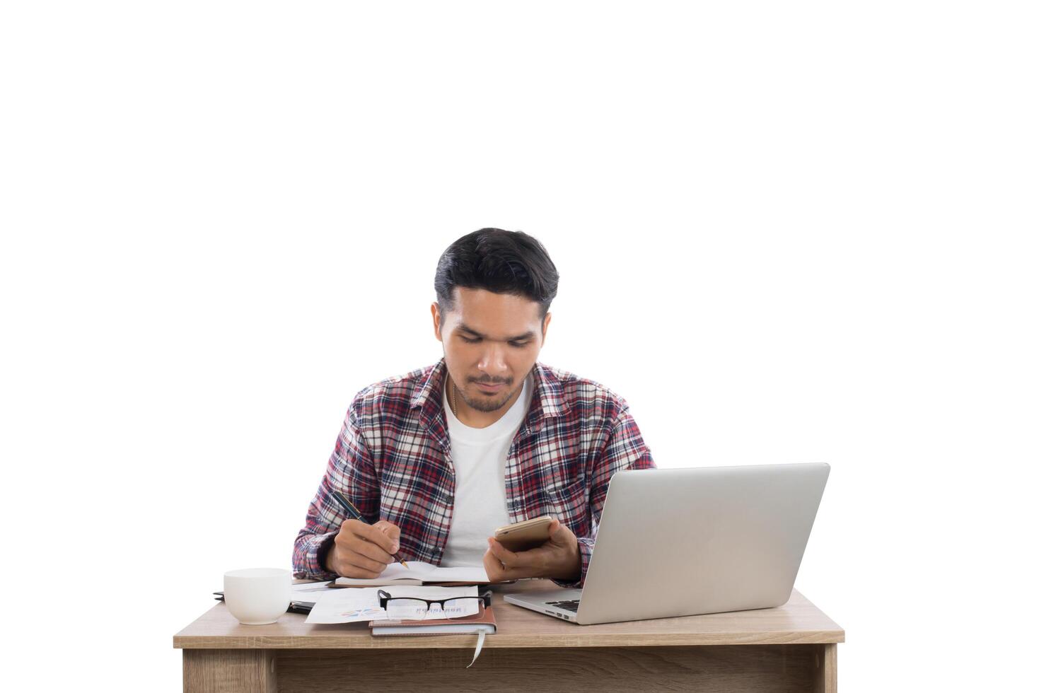 homme d'affaires regardant son téléphone tout en travaillant avec un ordinateur portable au bureau isolé sur fond blanc. photo