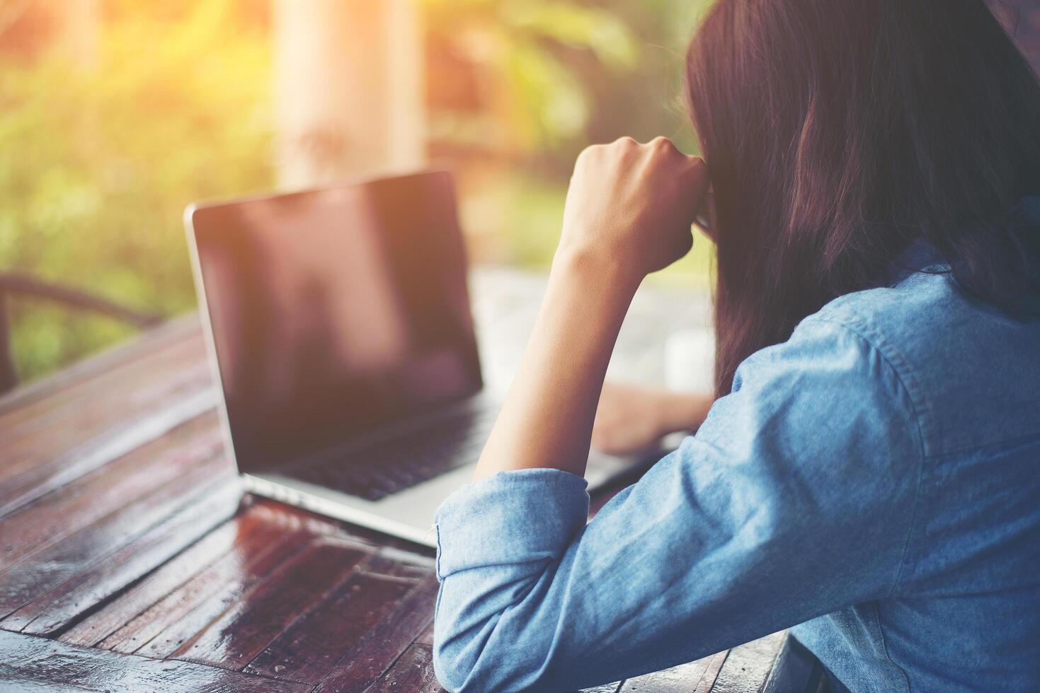 belle jeune femme hipster assise dans un café, détendez-vous et jouez avec son ordinateur portable, trouvez des informations sur le temps libre, heureux et amusant. notion de style de vie. photo