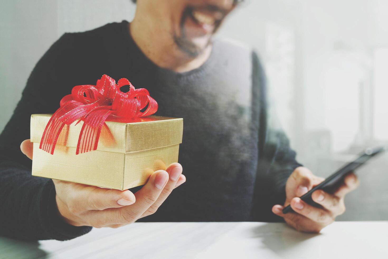 cadeau donnant la main créative en choisissant et la main avec un cadeau. livraison de cadeaux, surprise, utilisation d'un téléphone intelligent sur un bureau mable, effet de film filtrant photo