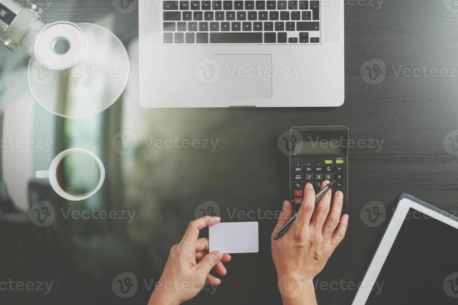 concept de magasinage sur internet.vue de dessus des mains travaillant avec une calculatrice et un ordinateur portable et une carte de crédit et un ordinateur tablette sur fond de table en bois foncé photo