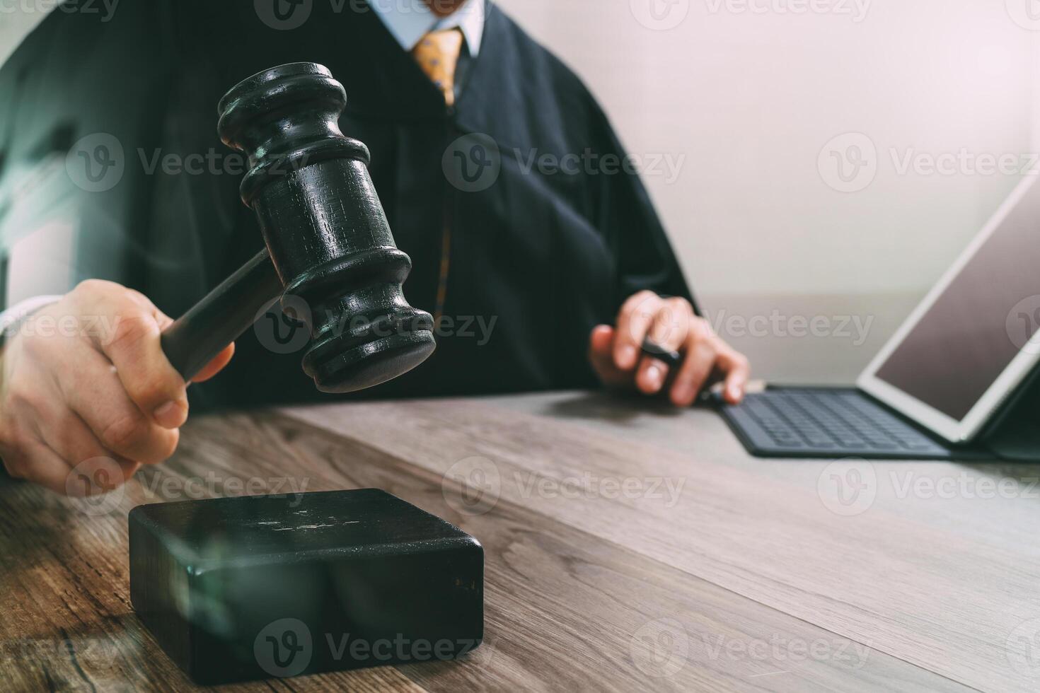 concept de justice et de droit. juge masculin dans une salle d'audience frappant le marteau, travaillant avec un clavier d'accueil d'ordinateur tablette numérique sur une table en bois, effet de filtre photo